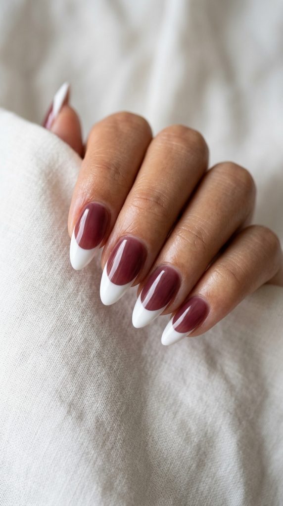 Classic French dip manicure with sheer nude or beige base and crisp white tips on almond-shaped nails